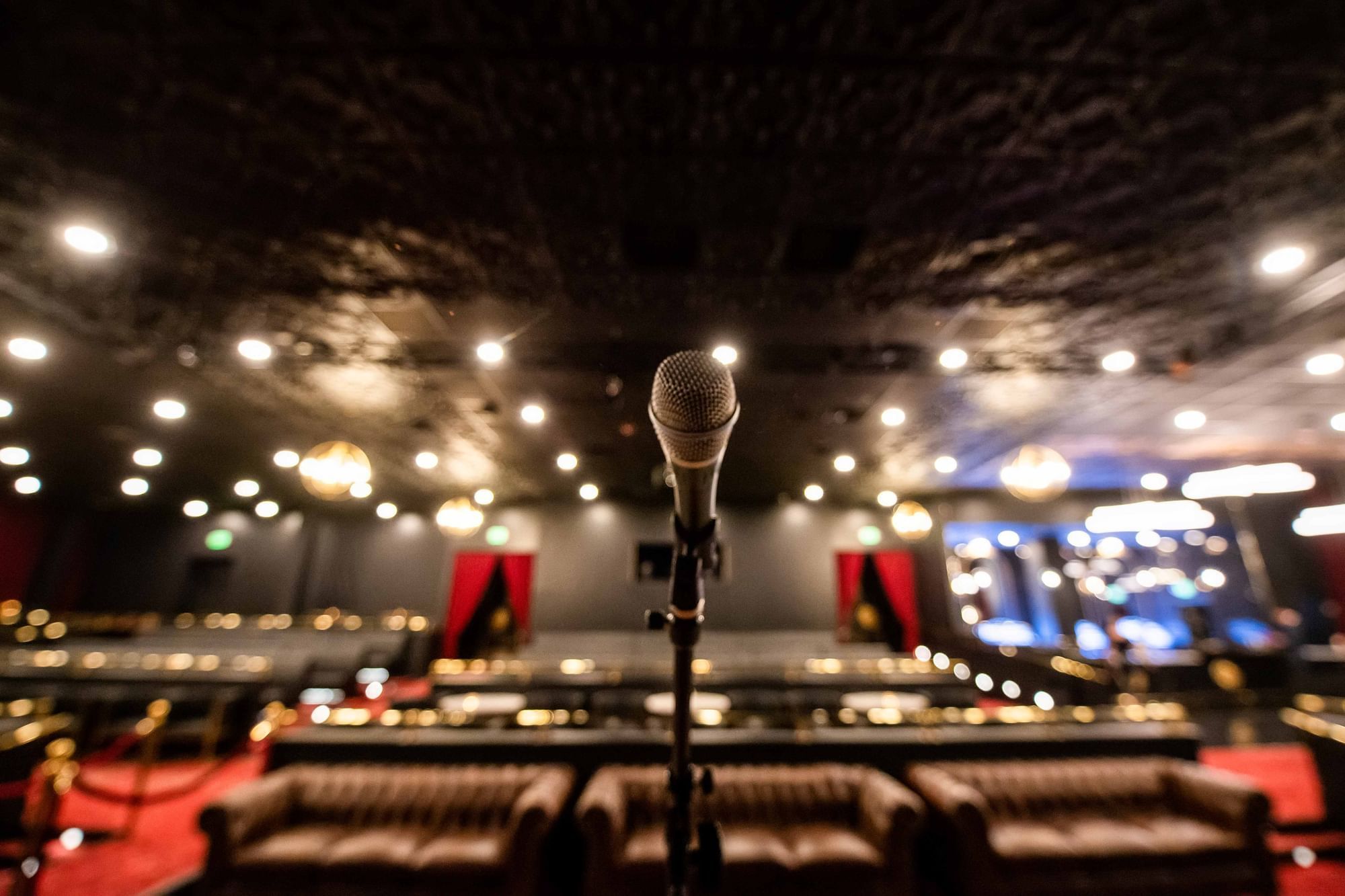 Microphone on a stand before leather sofas and lounge seating under warm ceiling lights at The Brook