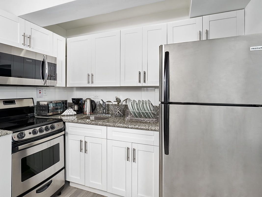 Modern kitchen at the Three Bedroom Penthouse Loft Suite with white cabinets, and granite countertops at R Hotel Kingston.