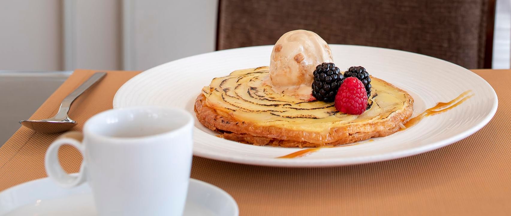Plate with a golden pastry topped with a scoop of ice cream and fresh berries at Téséo Restaurant