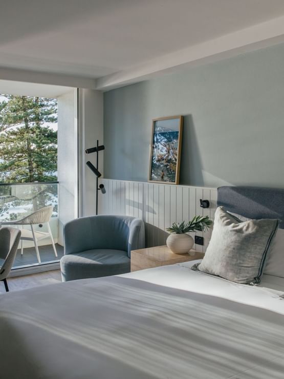 Ocean View Two Bedroom at Elysium Hotels bed with grey pillows beside a nightstand and framed wall art nearby