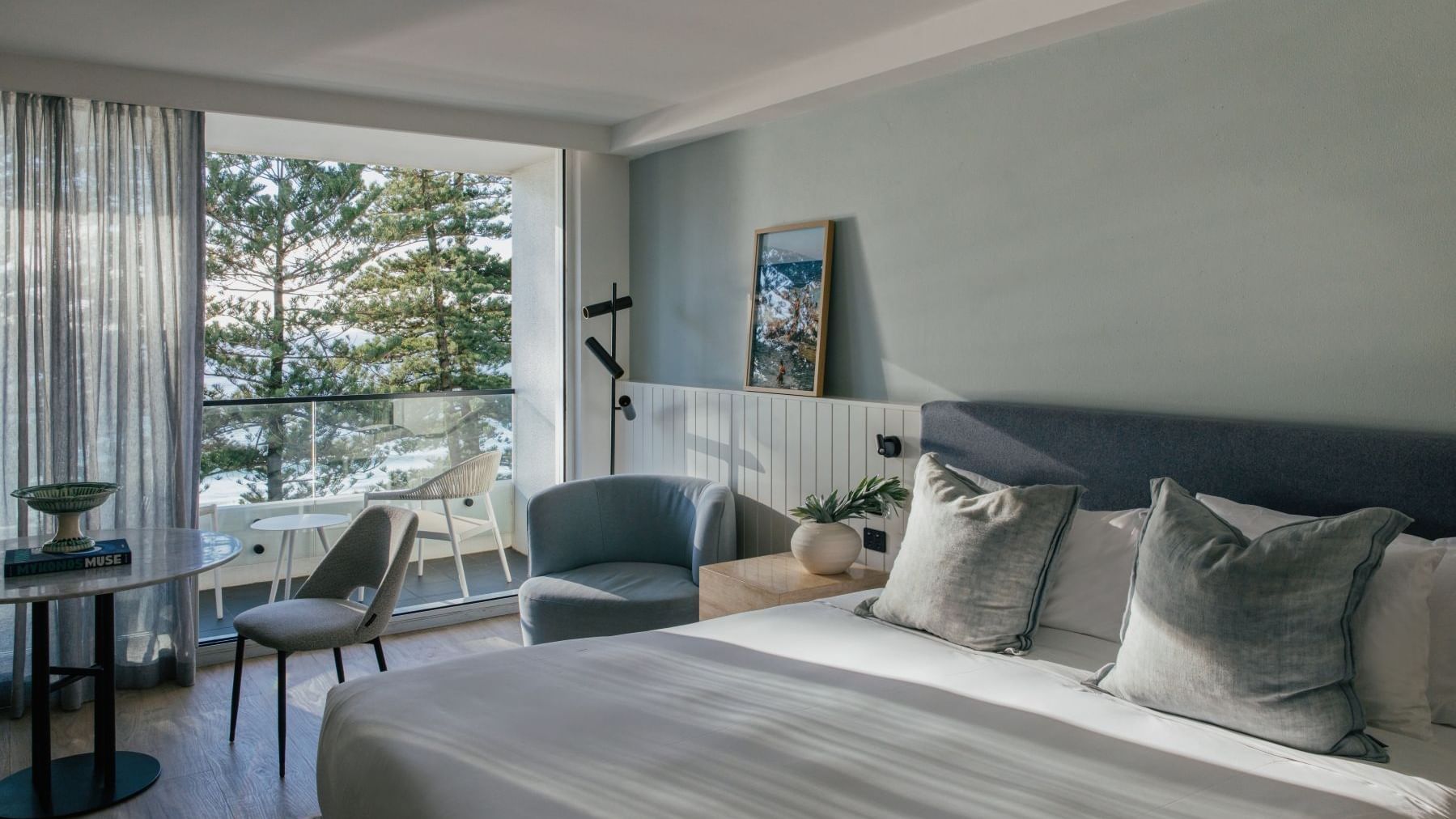 Ocean View Two Bedroom at Elysium Hotels bed with grey pillows beside a nightstand and framed wall art nearby