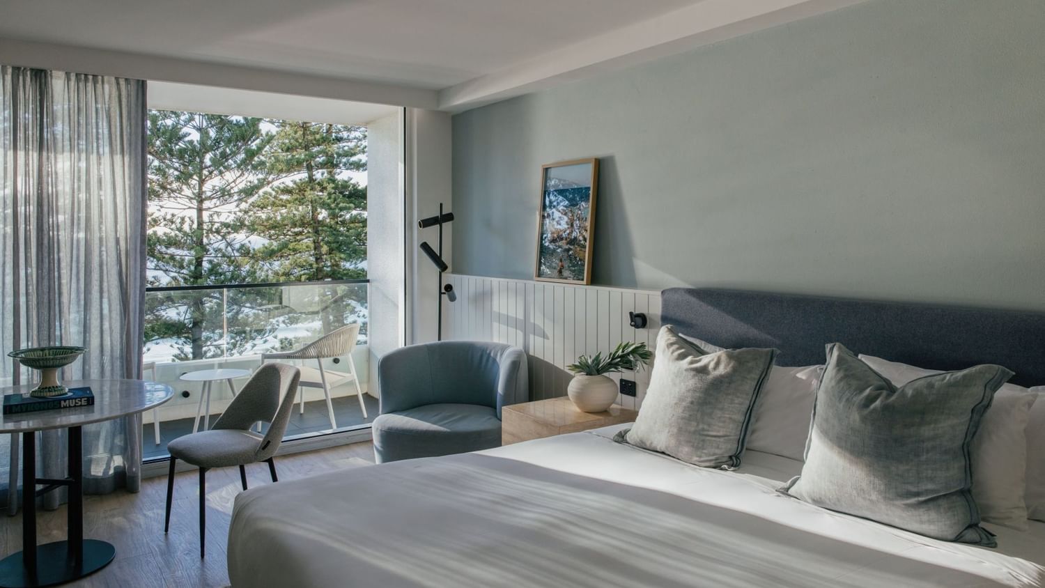 Ocean View Two Bedroom at Elysium Hotels bed with grey pillows beside a nightstand and framed wall art nearby