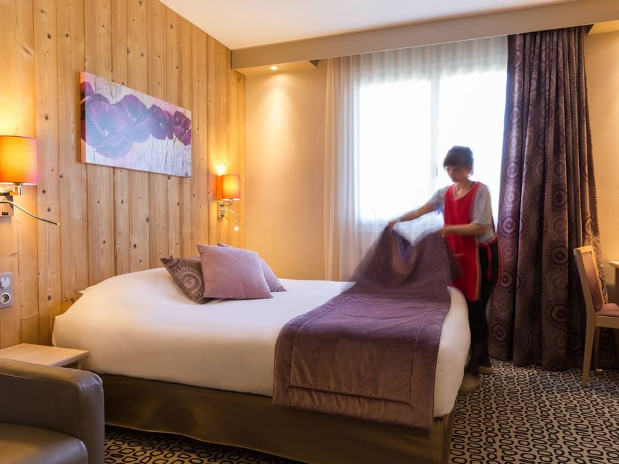 A maid preparing a bed in a room at Hotel Rey du Mont Sion