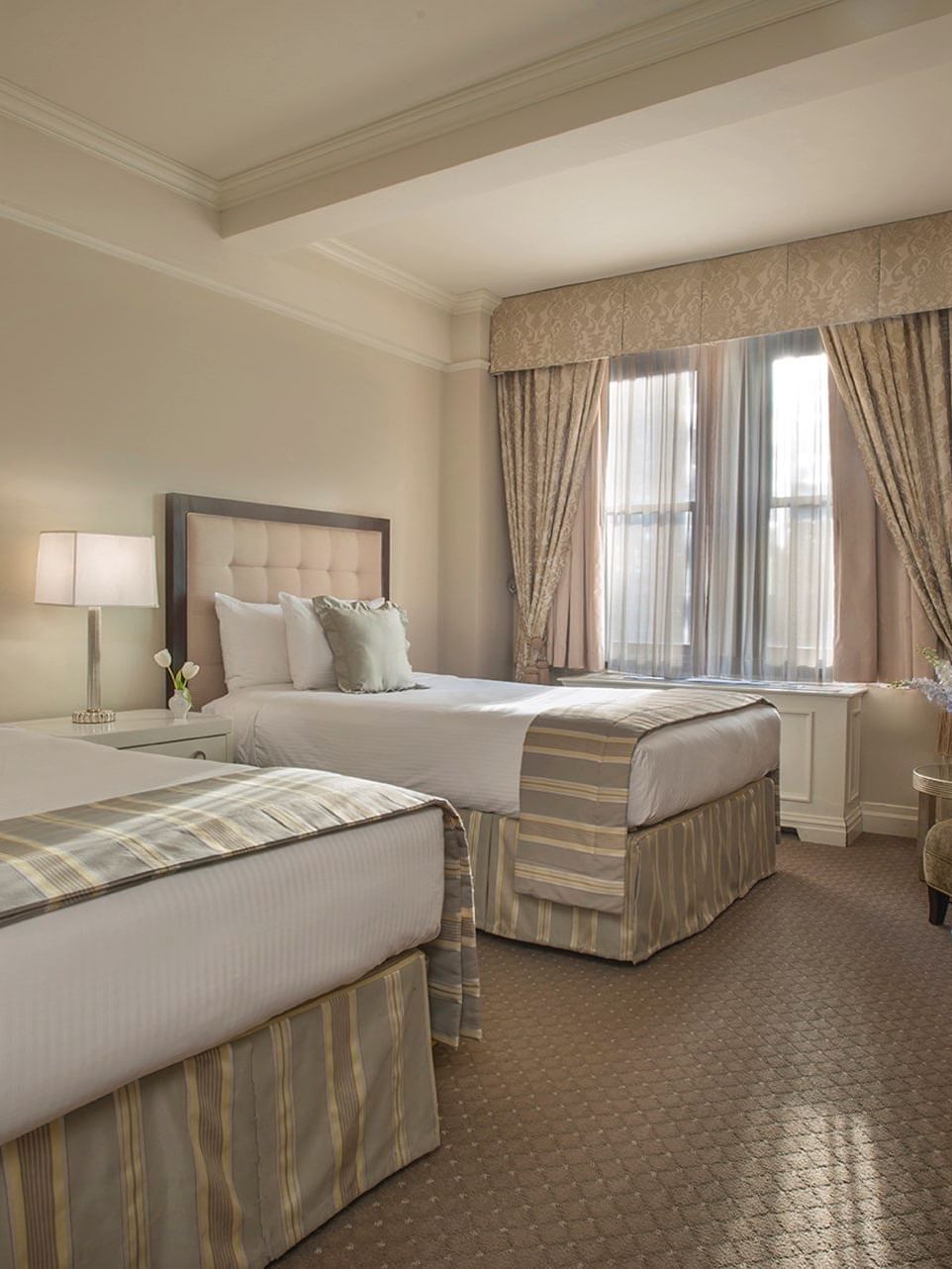 Beds with a side table and a couch by the window in Accessible Premier City View Two Double Beds at Warwick New York