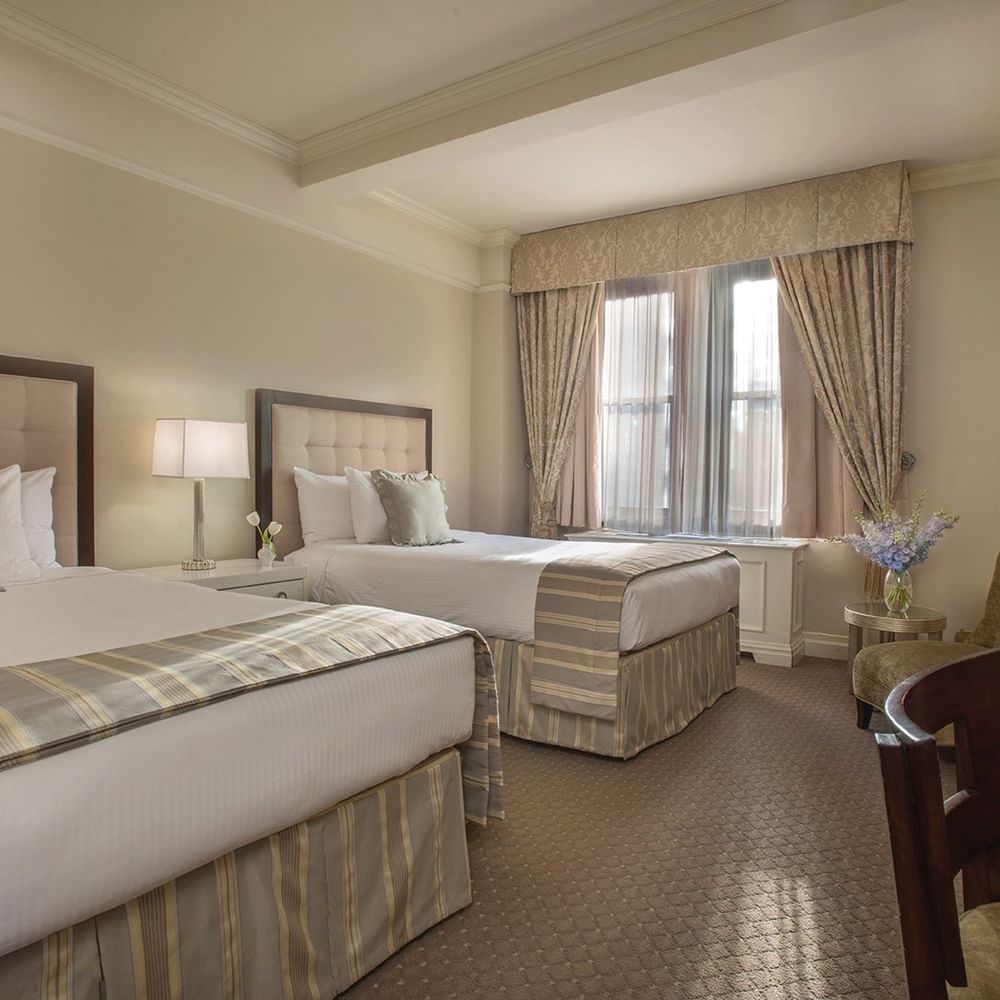 Beds with a side table and a couch by the window in Accessible Premier City View Two Double Beds at Warwick New York