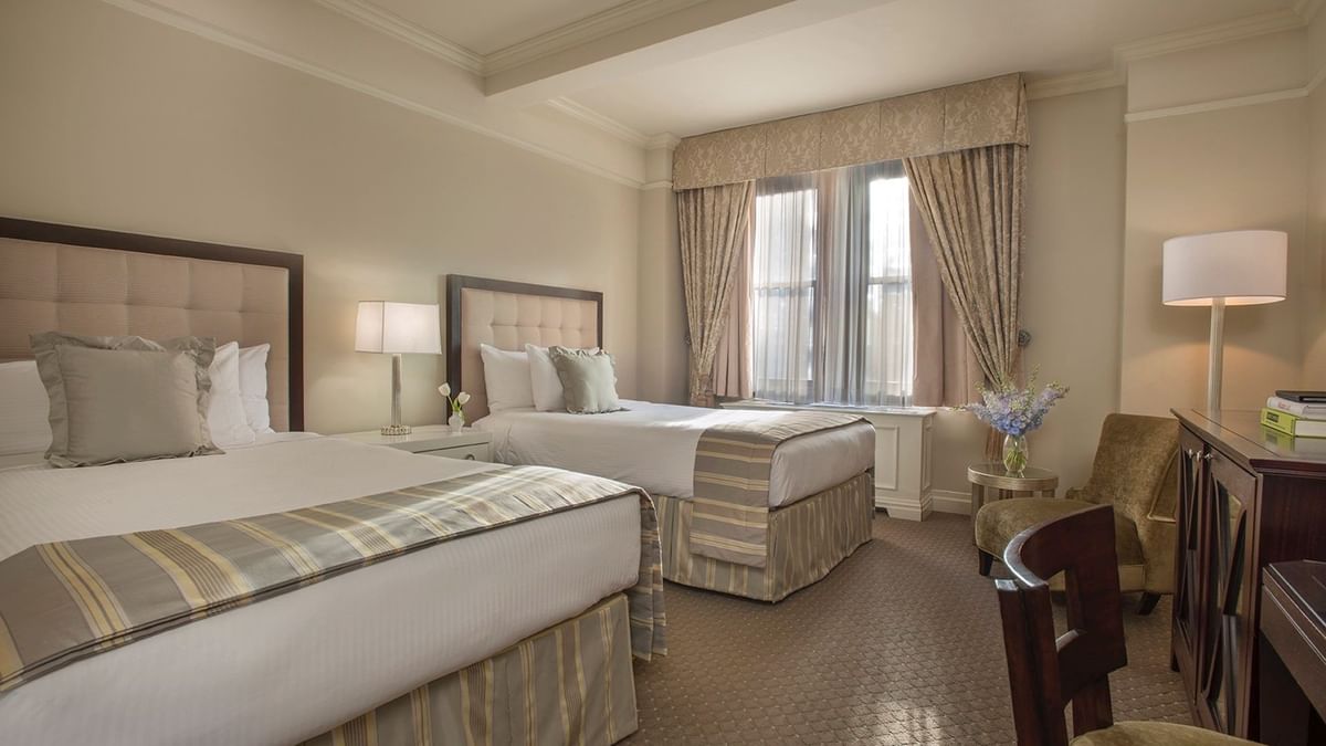 Beds with a side table and a couch by the window in Accessible Premier City View Two Double Beds at Warwick New York