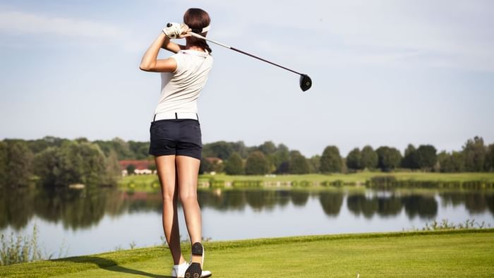 Back view of A lady hits a golf ball  near The Original Hotels
