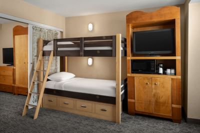 Bunk beds with ladder by a TV cabinet in room at Anaheim Portofino Inn, a Disneyland area hotel with renovated family suites