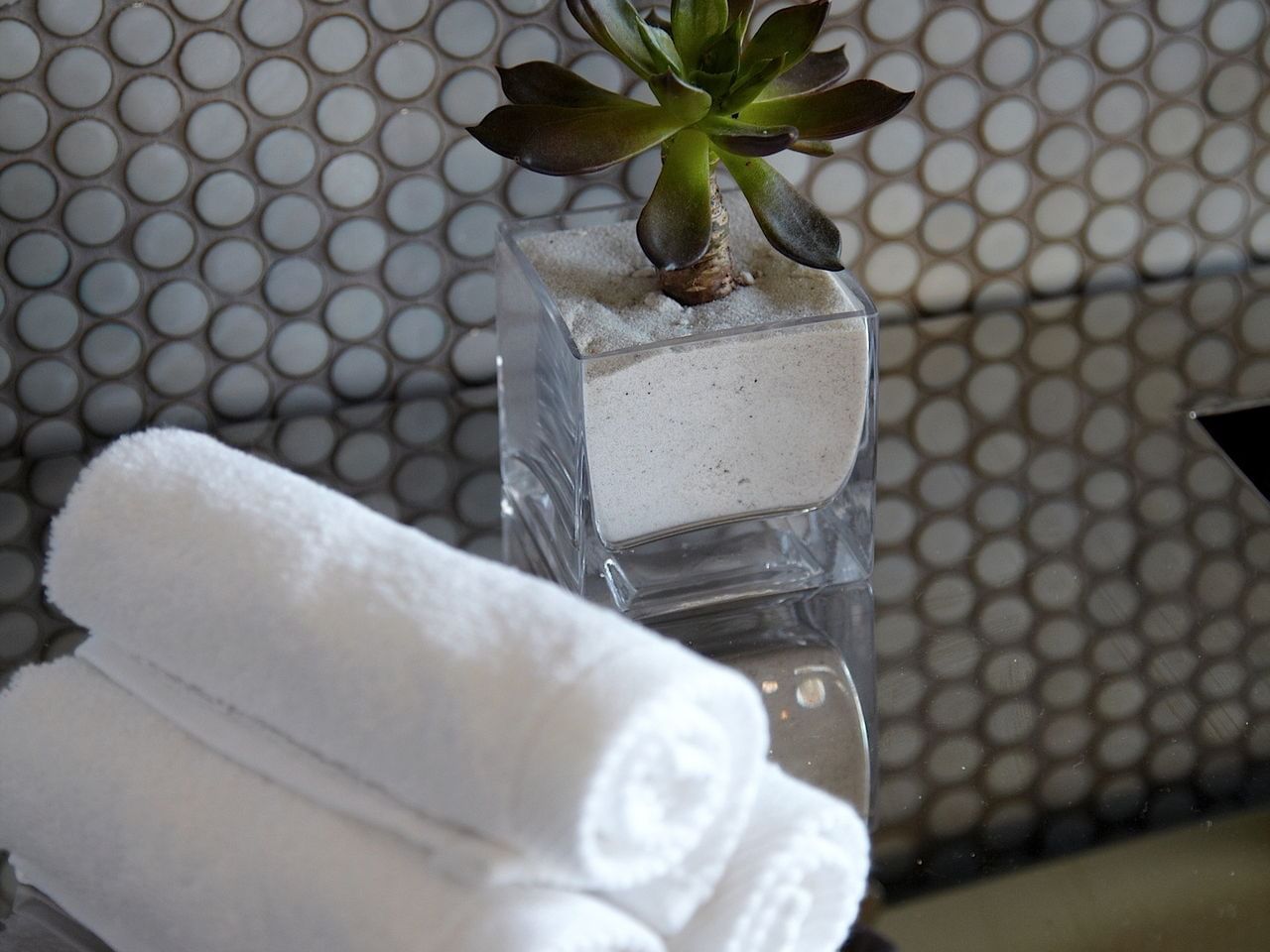 3 White towels on a table next to a plant at Dream Downtown NYC