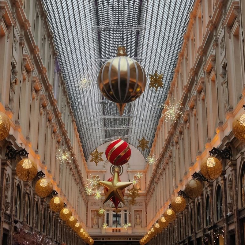 Ornate, arched shopping arcade with festive decorations, including large golden and red ornaments, and star hanging from the ceiling.