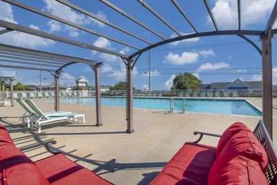 Sunny pool area at Ogunquit Hotel and Suites with a large pool, lounge chairs, and a pergola under a bright blue sky