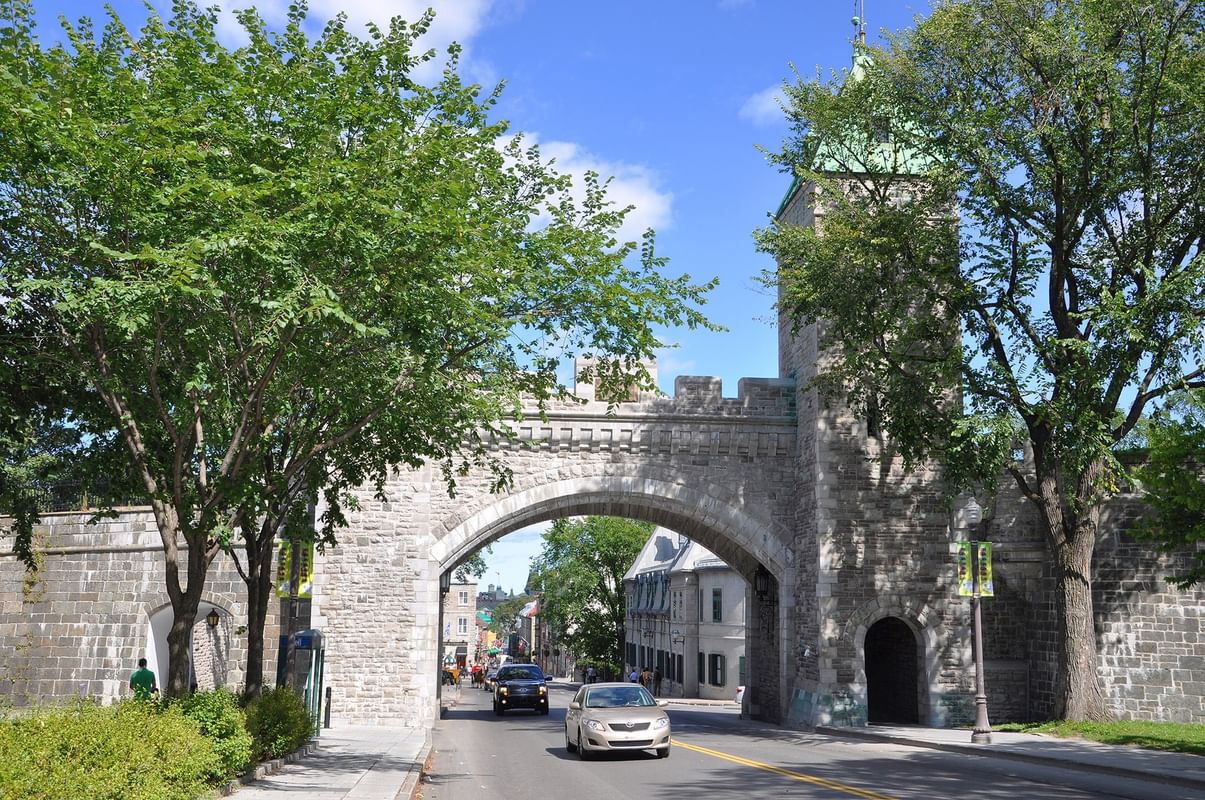 Rue pavée avec pont en arc de pierre et voitures en mouvement près de Warwick Le Crystal Montréal