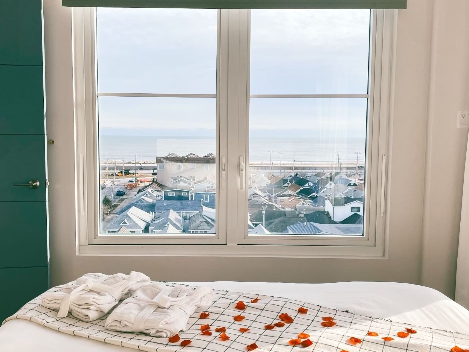 Bed with folded robes & petals near window, The Rockaway Hotel