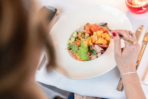 Healthy bowl with avocado and salmon by a fork on a white cloth table at Warwick Geneva