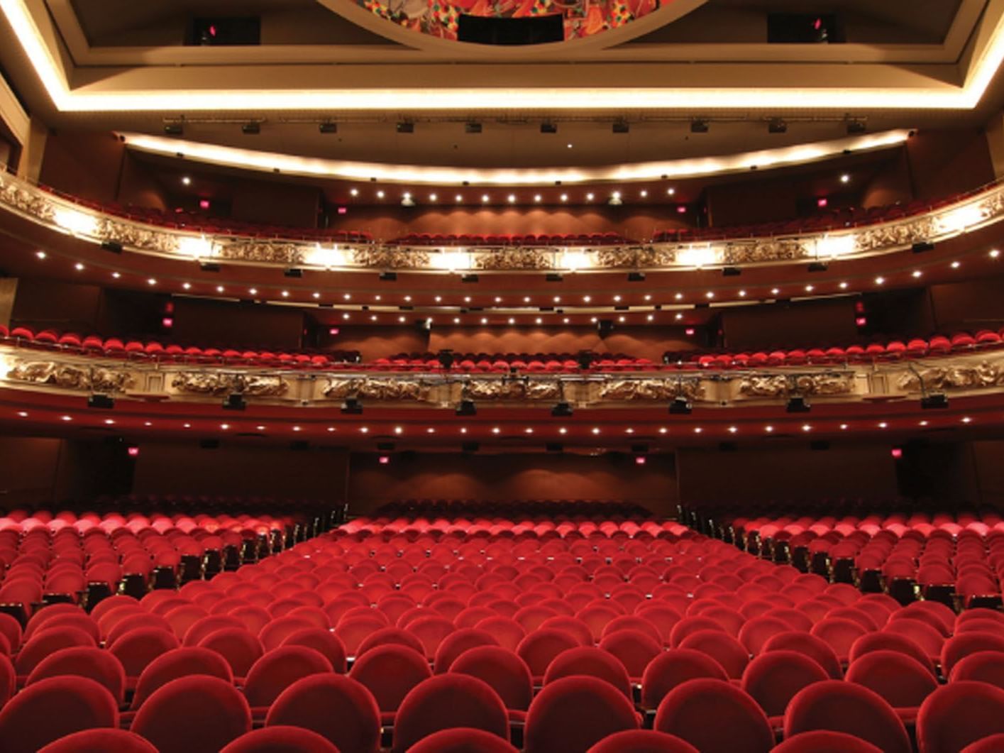 Red seats in a multi-tiered theater with decorative golden accents by The Princess Of Wales Theatre near Hotel X Toronto