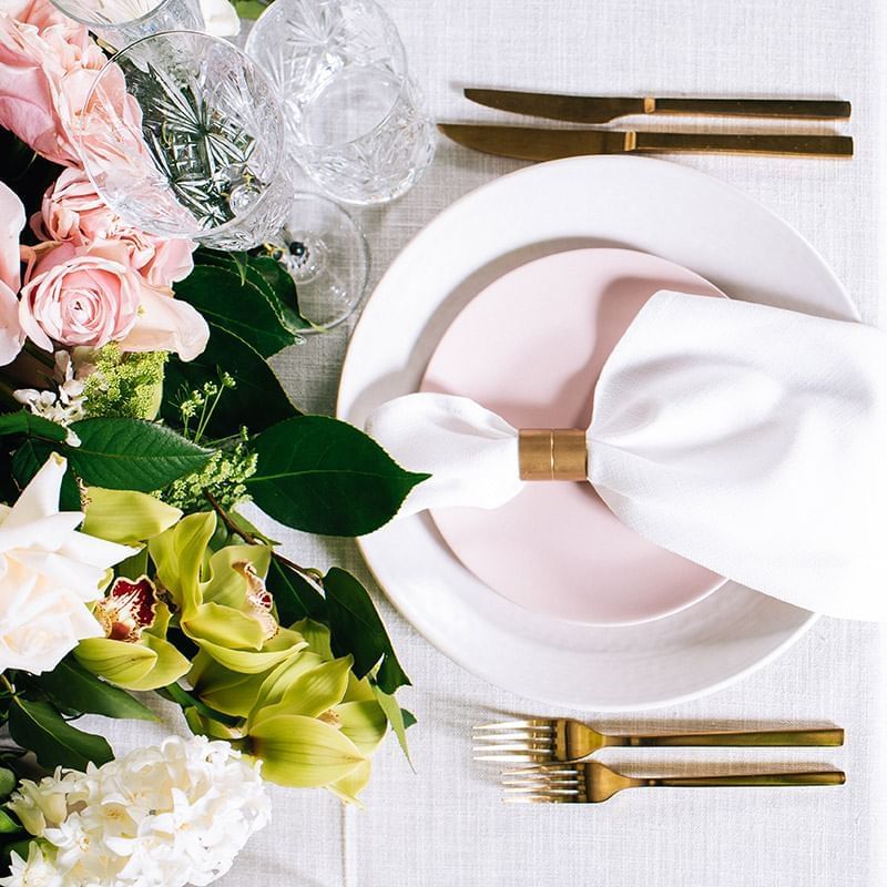 Elegant table setting with pink napkins, gold cutlery, and flowers at Crown Hotels Melbourne