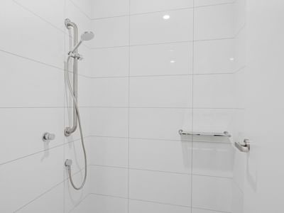 White shower with tiled walls and showerhead at UniLodge Brisbane City.