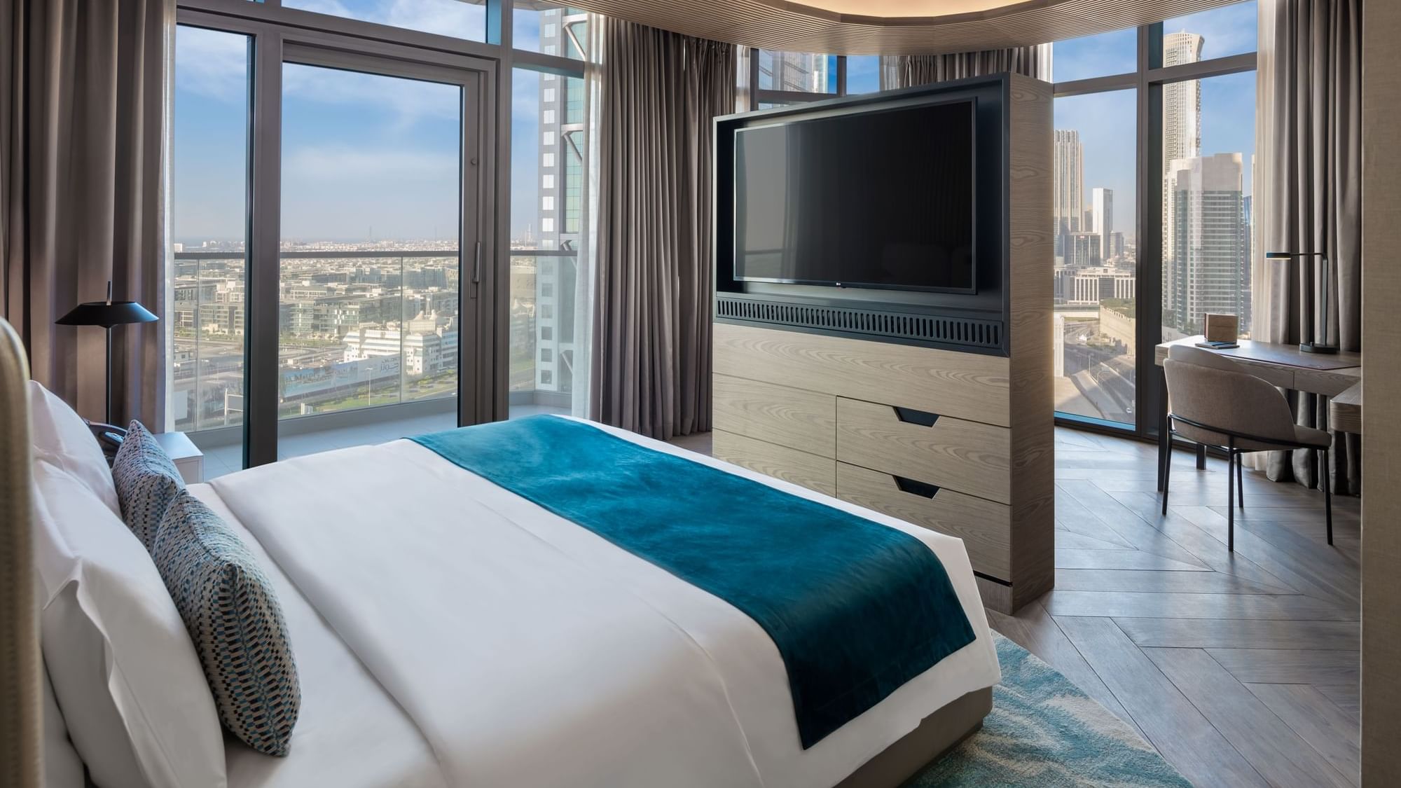 Modern, elegant bedroom at Paramount Hotel Midtown with a large, rotating TV stand and panoramic views of the city skyline