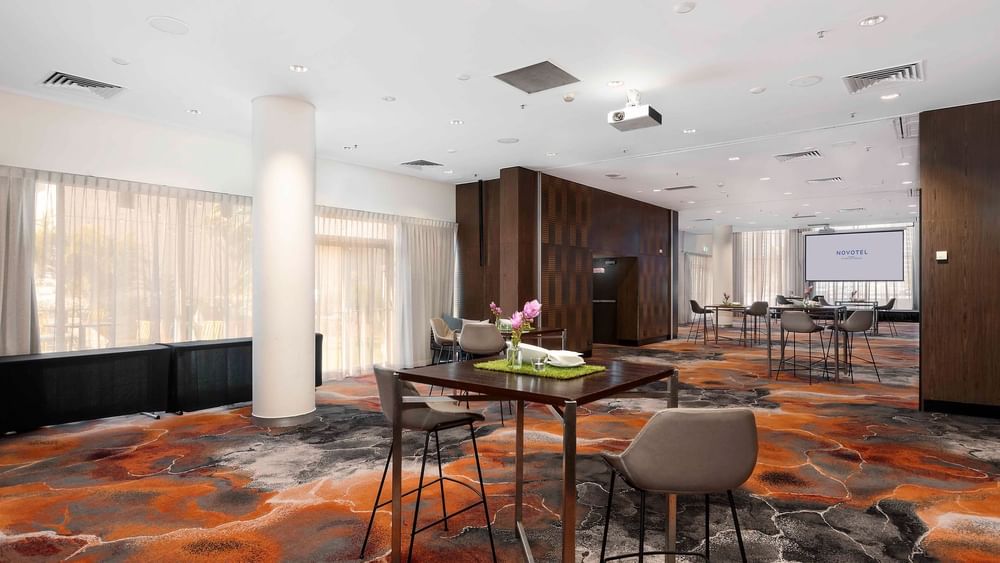 Breakout space by The Hunter Room 1–4 featuring high tables and a projector at Novotel Sydney on Darling Harbour