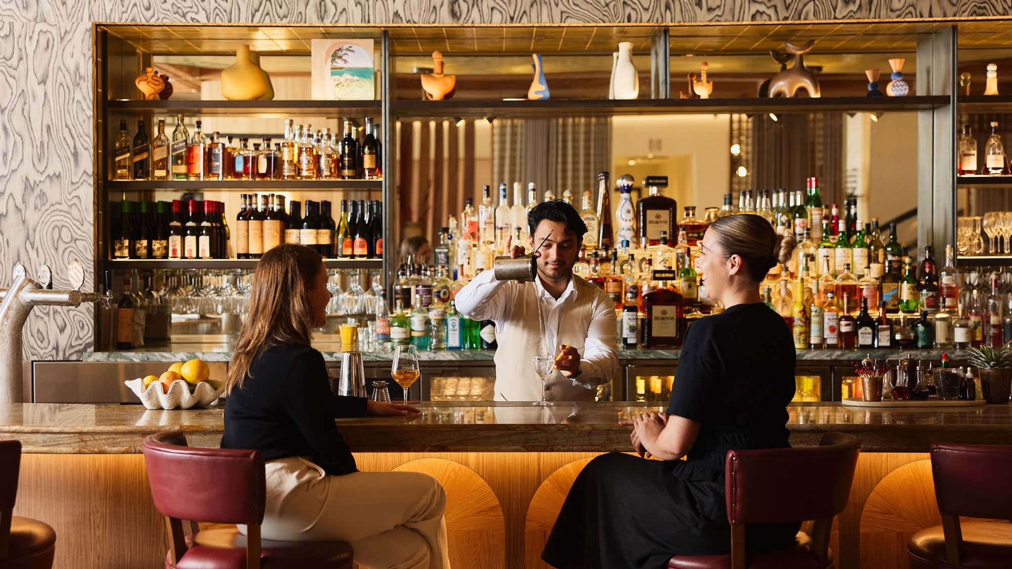 Cibaria\'s 55 North Bar at Elysium Manly with guests on red stools by a marble counter, highlighting top bistro Manly