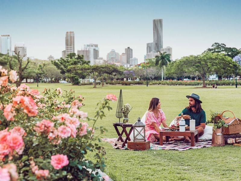 Couple enjoying a picnic in New Farm with a city skyline near Sofitel Brisbane Central