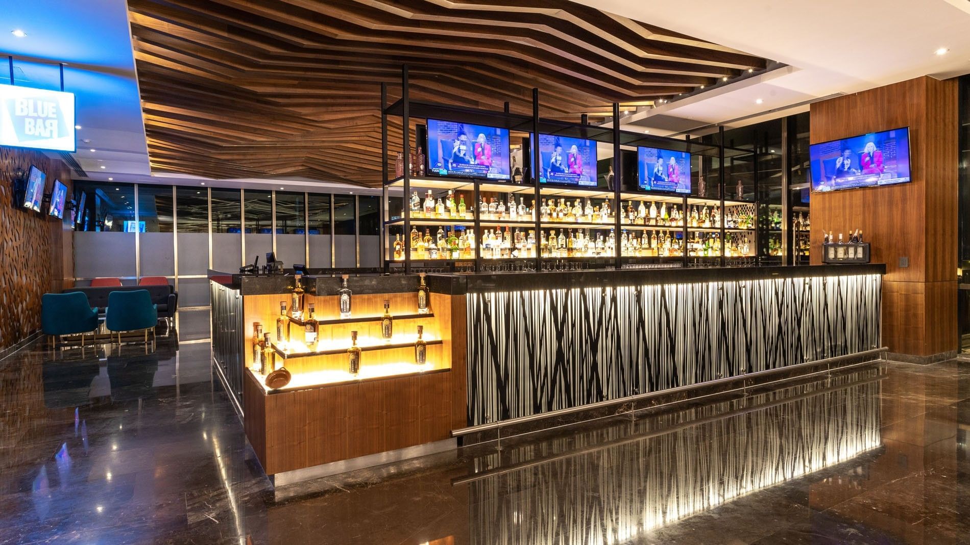 Close-up of the blue bar counter with backlit shelves for premium liquor at Camino Real Fashion Drive, Monterrey