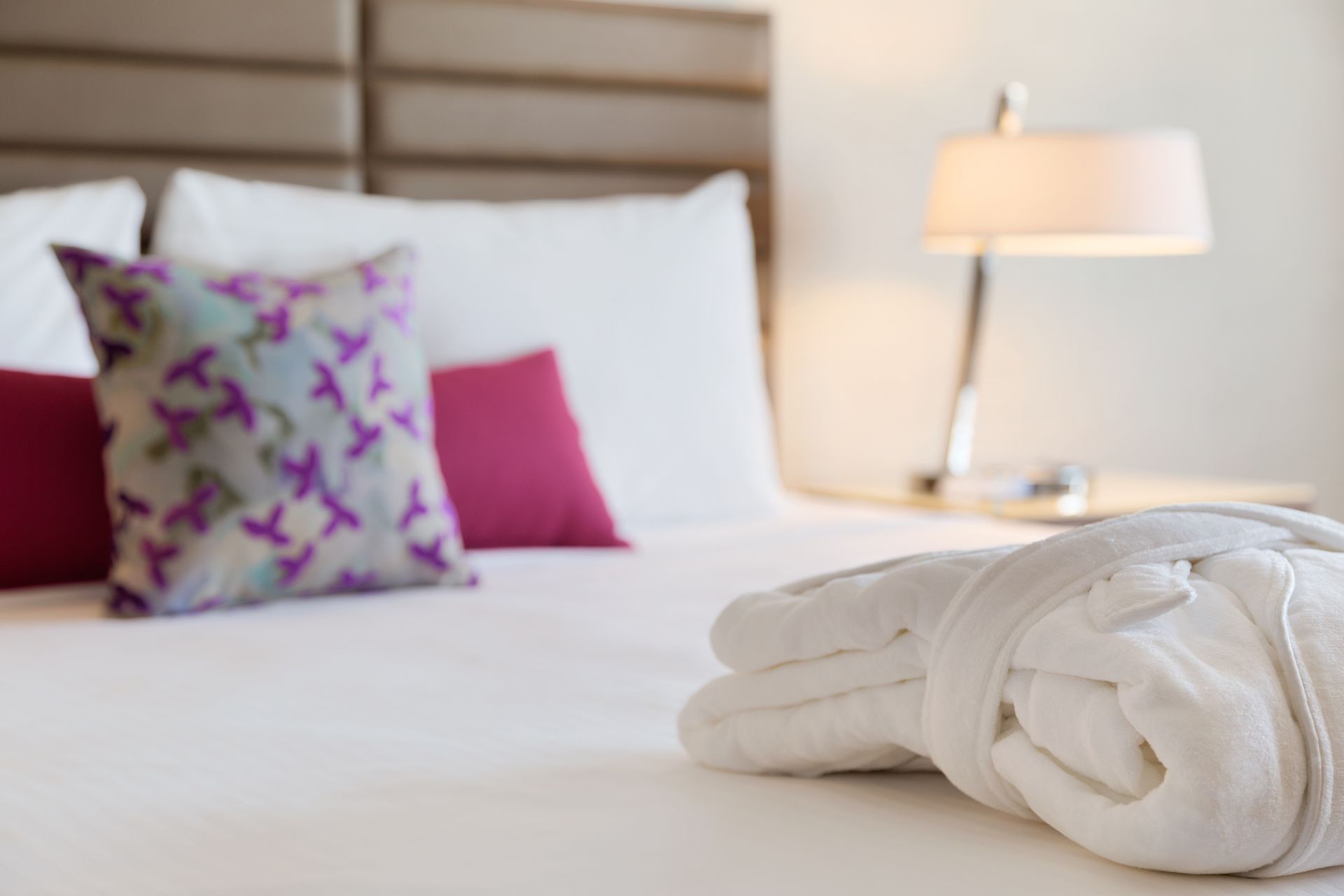 White robe on cozy bed with decorative pillows