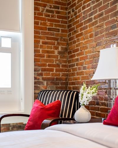 Striped chair, nightstand & cozy bed in Queen Premiere at Retro Suites Hotel