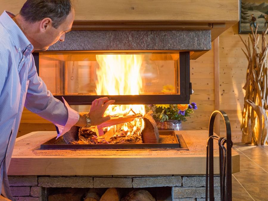 A man in front of the wood stove at Chalet hotel le beausoleil