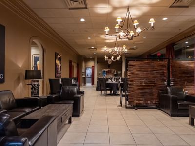 Elegant dining area with chandeliers and black leather furniture at Carriage House Hotel & Conference Centre
