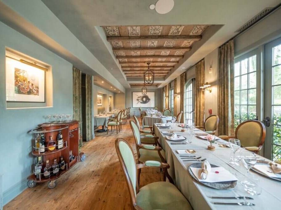 Elegant Alba Room at Granduca Houston with a long table set with fine tableware, vintage decor, and a wooden bar cart