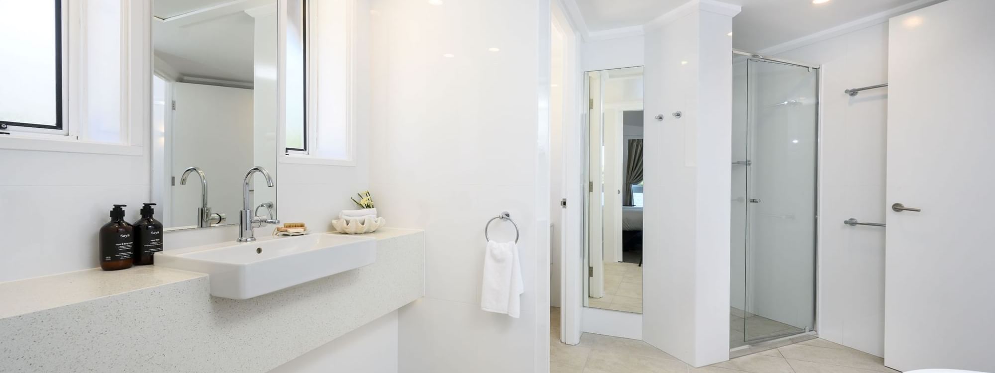Vanity with various toiletries by the glass shower in the Deluxe Overwater Bungalow at Novotel Sunshine Coast Resort