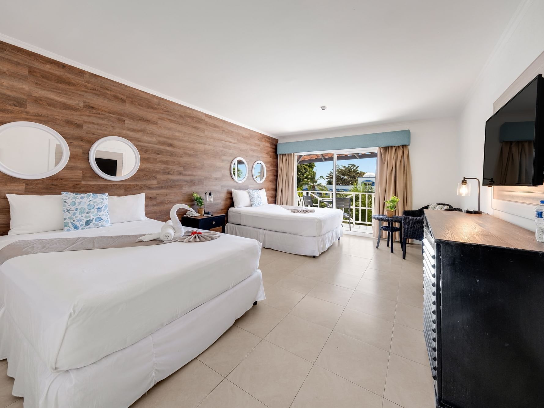 Garden View room with two beds, wood accent wall, and balcony overlooking greenery at Playa Blanca Resort, Rio Hato.