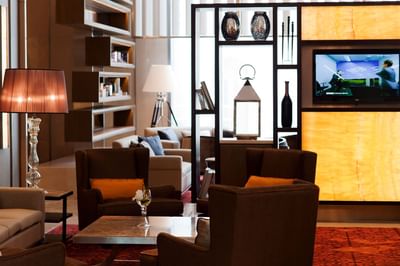 Lobby area with comfy sofas, lamps & TV at Eastin Hotels