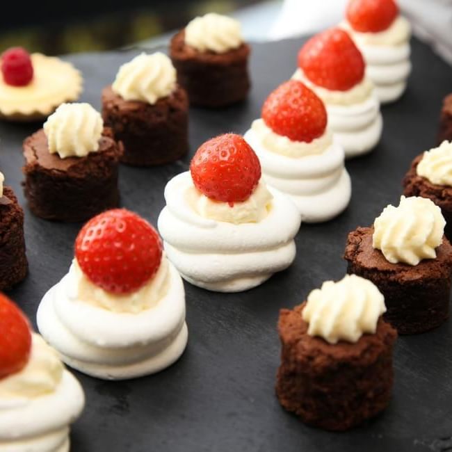 Array of sweet canape ideas featuring mini strawberry meringues, brownie bites and raspberry custard tartlets 