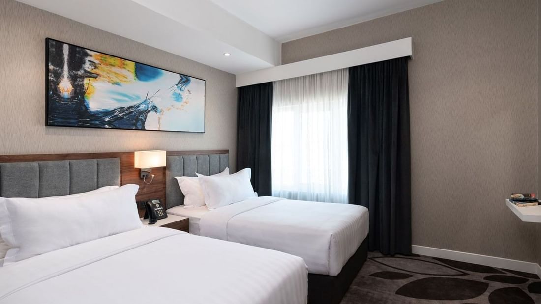 Executive Room City View features Twin beds in a room by a dark floral rug and a wall-mounted art piece at Warwick Al Jubail