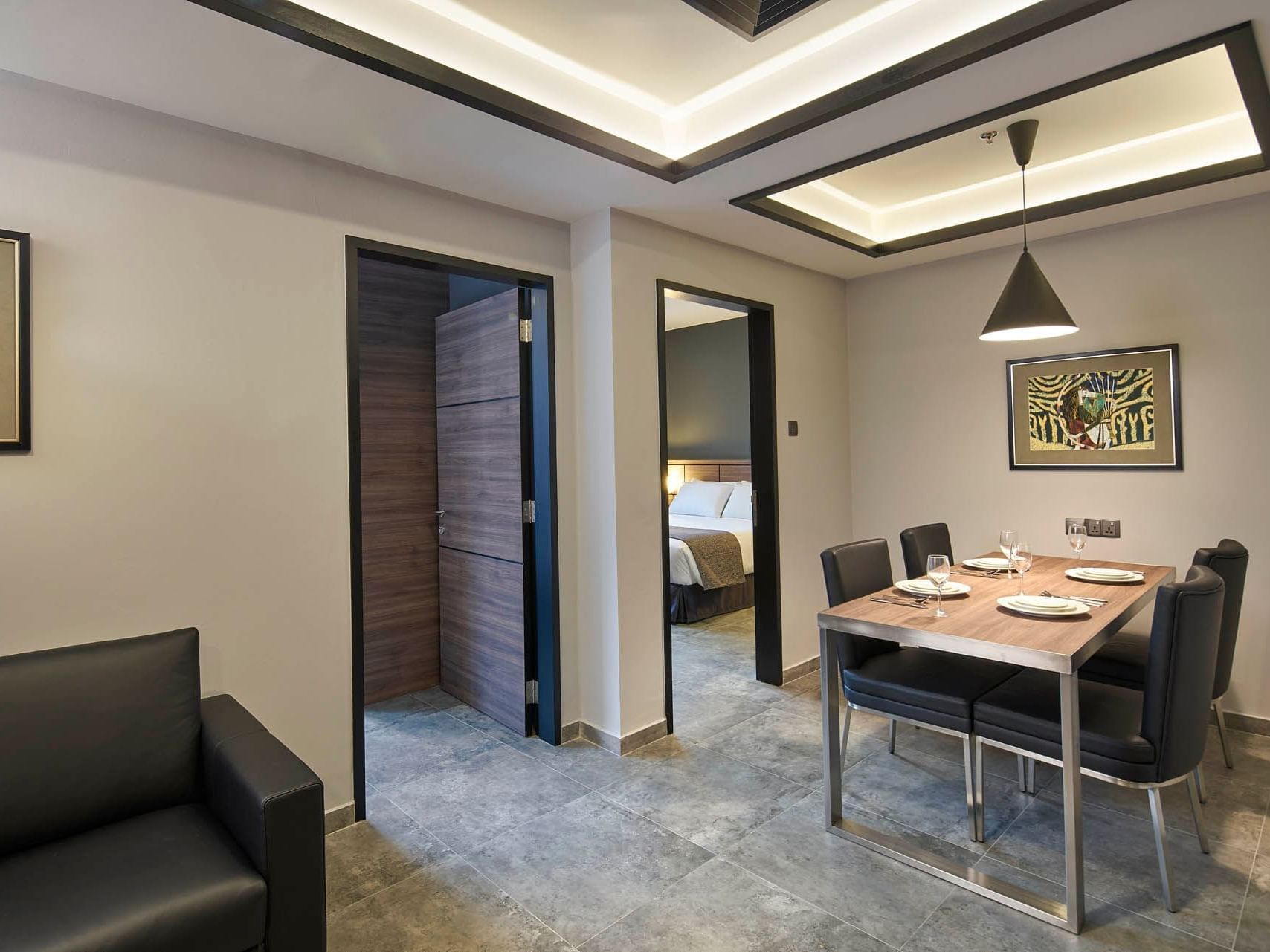 Image 77: Modern two-bedroom dining area with a wooden table and access to the bedroom and bathroom at Orchard Grand Court