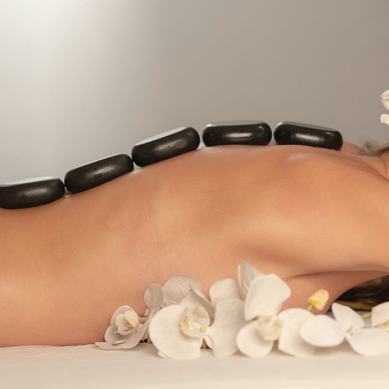 Close-up of Hot stones & orchid flowers placed by a lady in the spa at Côte d'Azur Resort