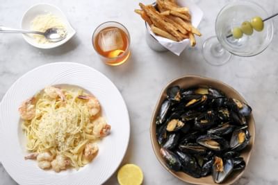 plate of seafood pasta and mussells, french fries and two cockta