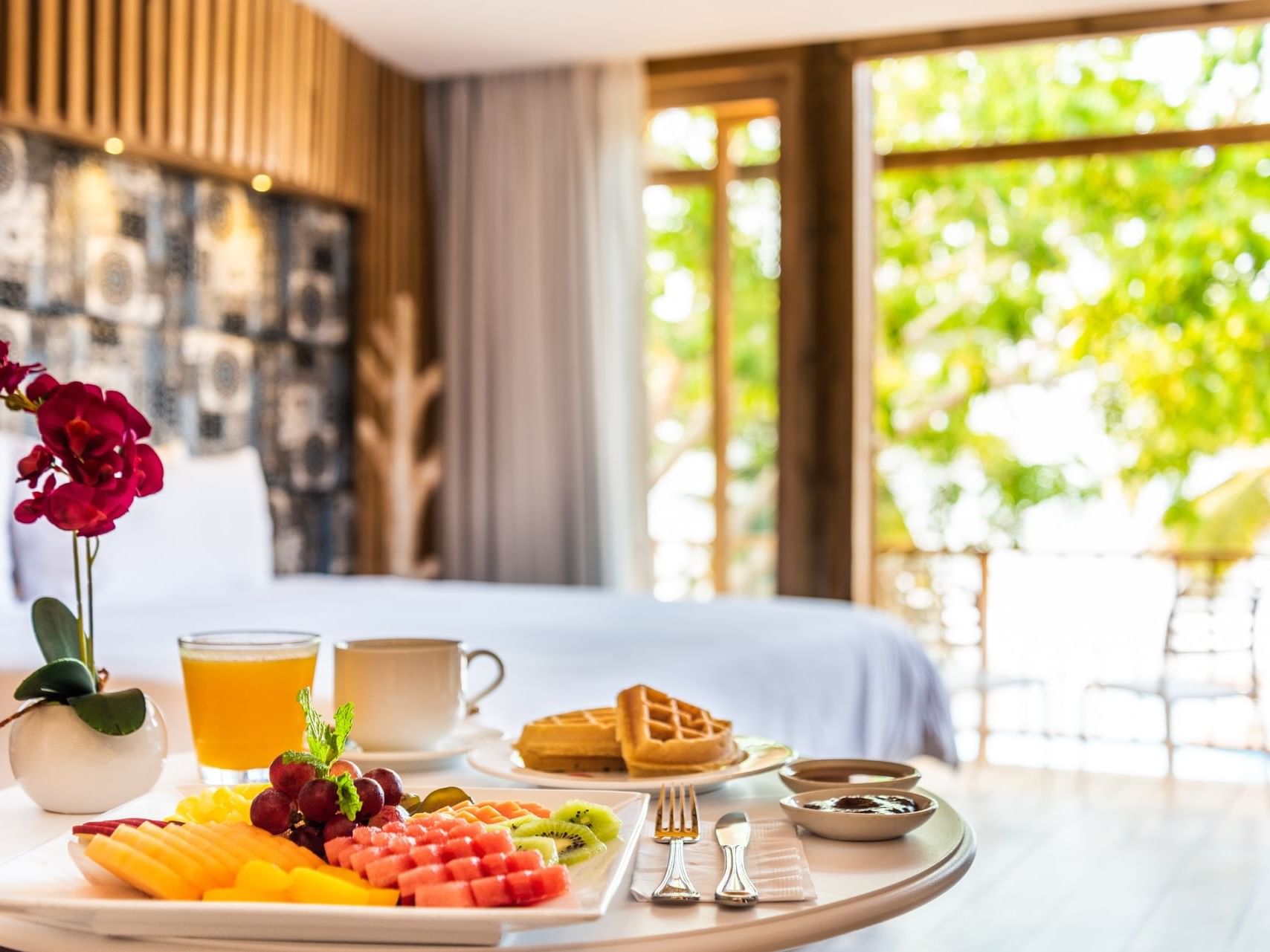 Breakfast with fruits, waffles and orange juice served on a table in the room at Hotel Isla Del Encanto