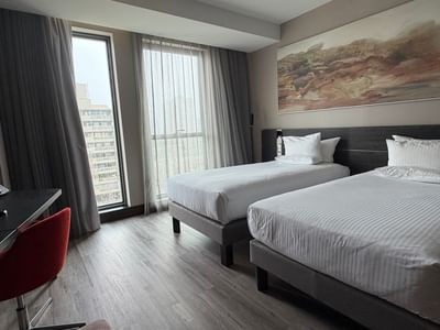 Standard Room with Two Single Beds featuring twin mattresses and a workspace desk near the window at Veranda Hotel