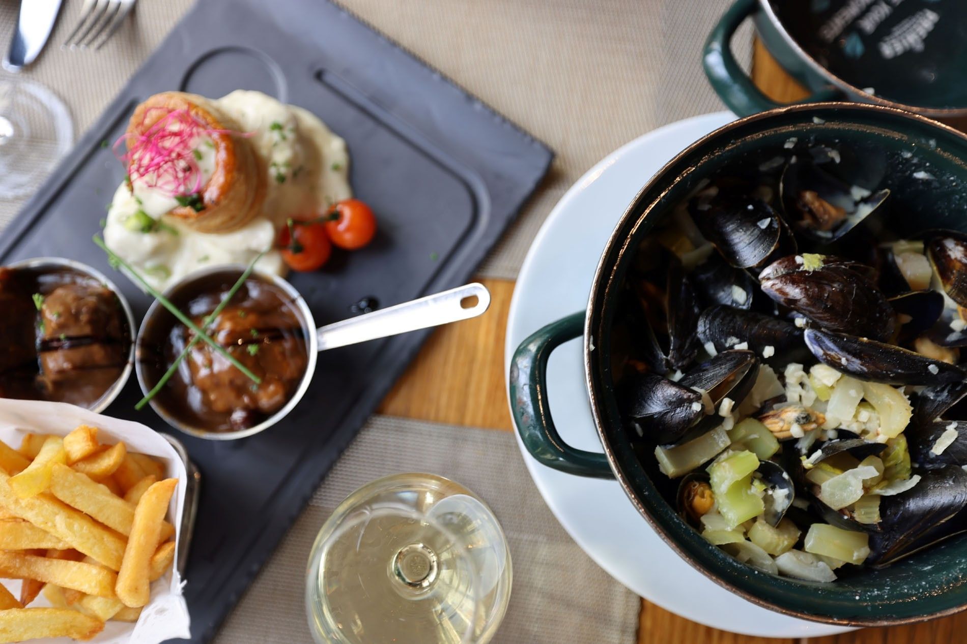 Mussels in a green pot by French fries, dipping sauces served in Chutney’s Restaurant at Warwick Grand Place Brussels