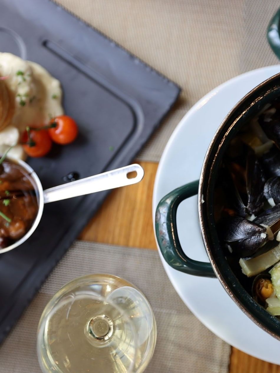 Mussels, fries, and sauces on a plate with a wine glass at Warwick Gourmet Retreat.