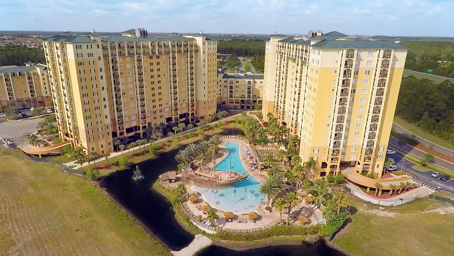 An aerial view of a resort with multiple buildings, a pool, and a water feature.