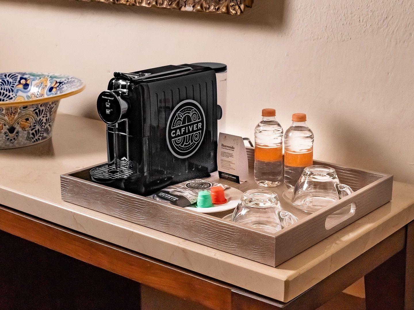 King Presidential Suite coffee station with a Cafiver espresso machine, water bottles, and glass cups at Quinta Real Puebla