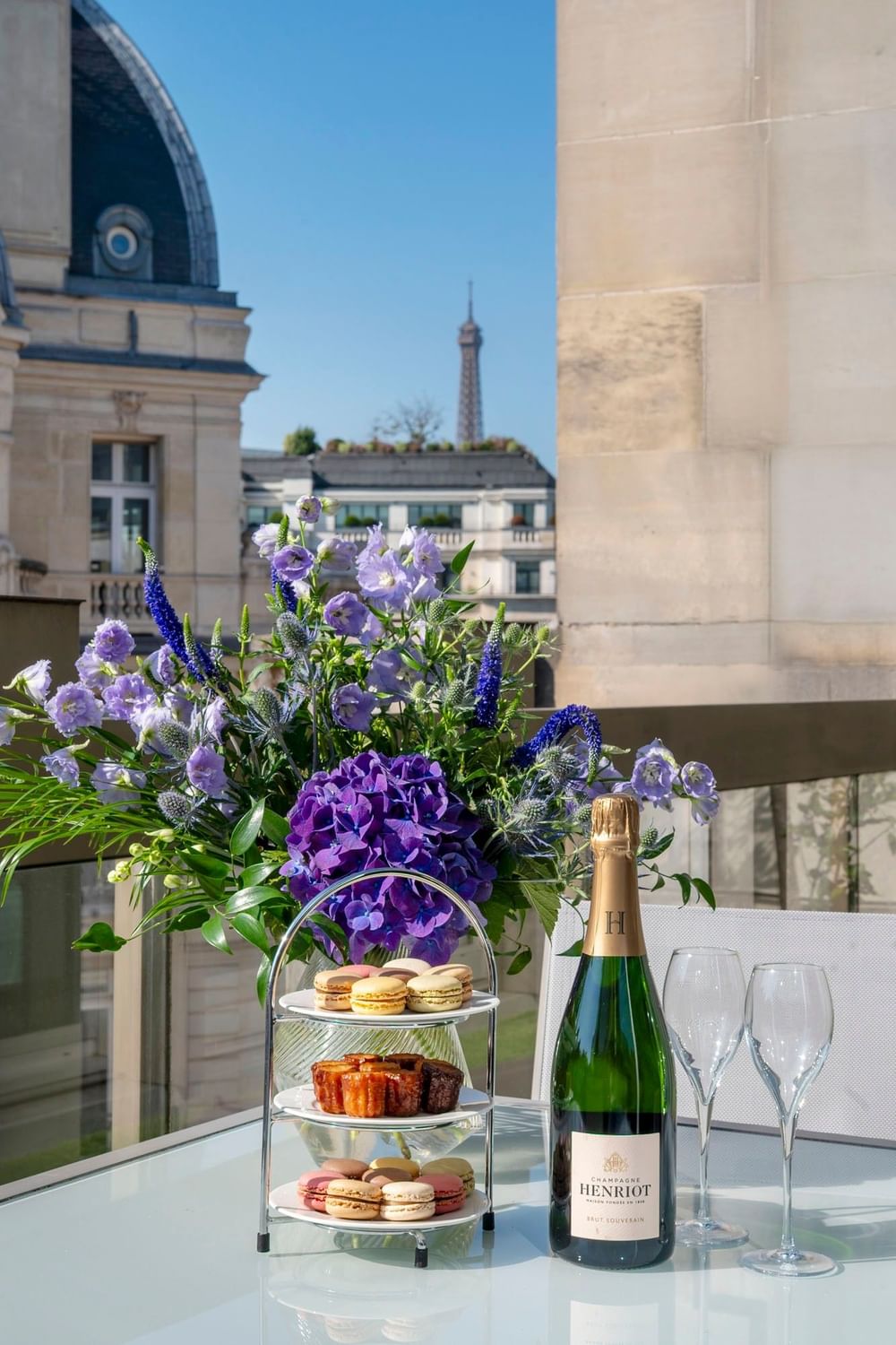 Bottle by purple flowers under the Eiffel Tower, surrounding a table at Saja by Warwick Paris Champs Elysées