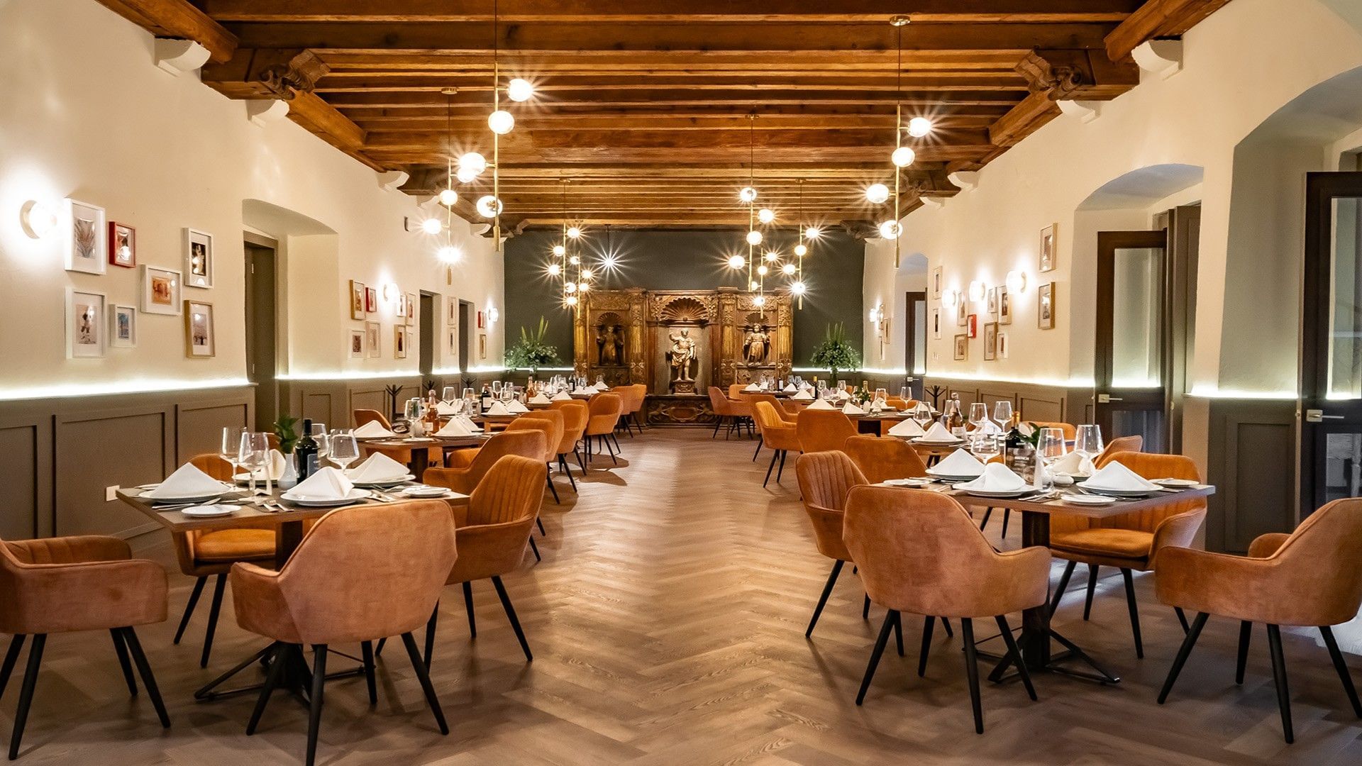 Spacious dining room with orange chairs, wooden beams, and orb lighting fixtures in Tierra Mia at Quinta Real Puebla