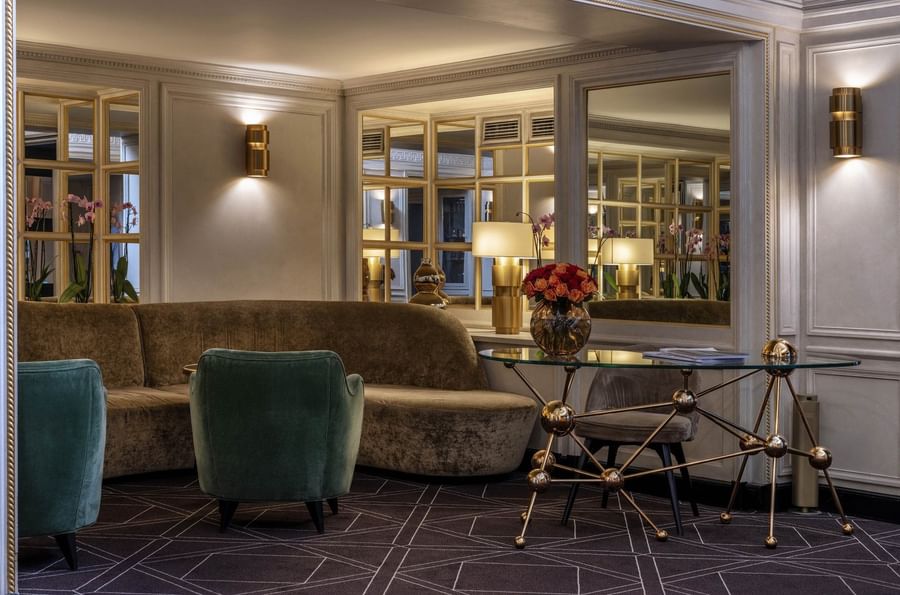 Velvet sofa and green armchairs by a geometric glass table in lobby at Hotel Barsey by Warwick