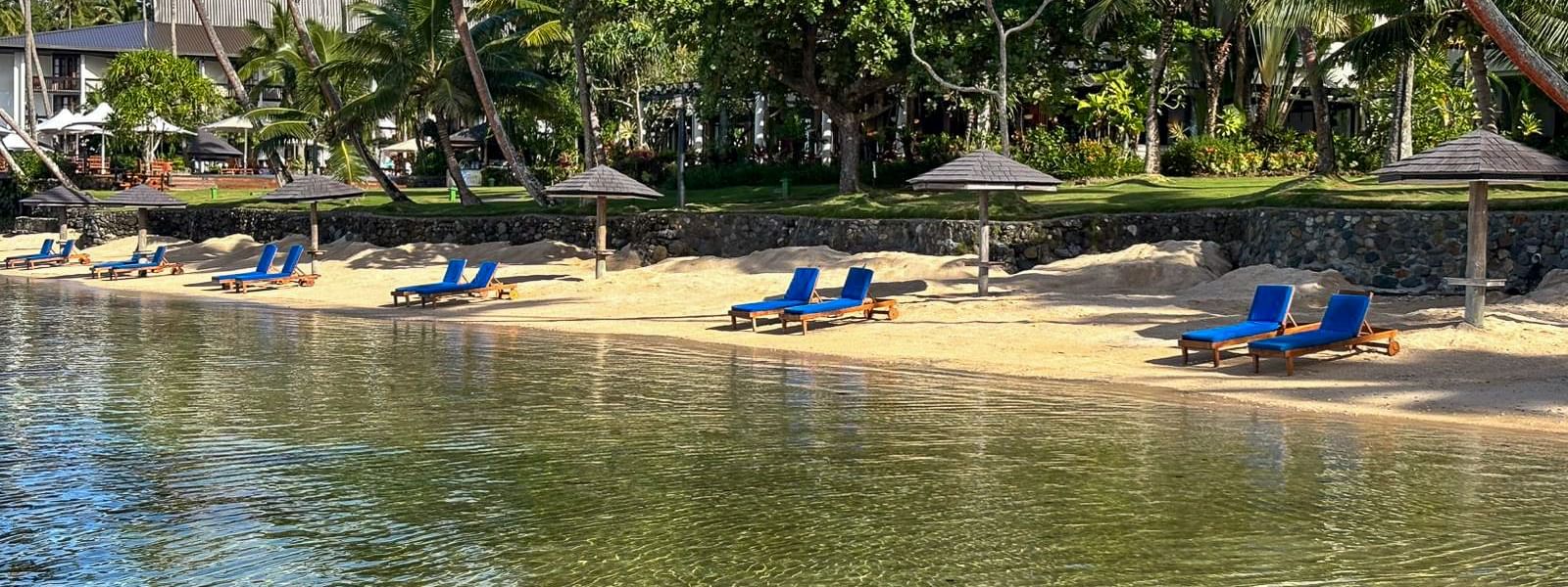Sand beach with lounge chairs and umbrellas at Warwick Fiji Resort and Spa in Korolevu