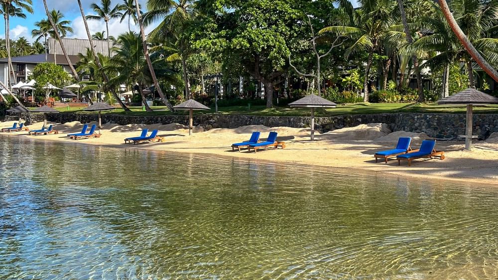 Sand beach with lounge chairs and umbrellas at Warwick Fiji Resort and Spa in Korolevu.